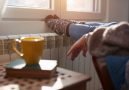 Woman,Heating,Feet,On,A,Chilly,Winter,Day,,Energy,And
